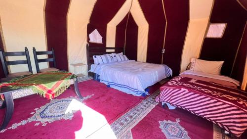 a bedroom with two beds and a pink rug at Sahara Luxury Camp in Zagora