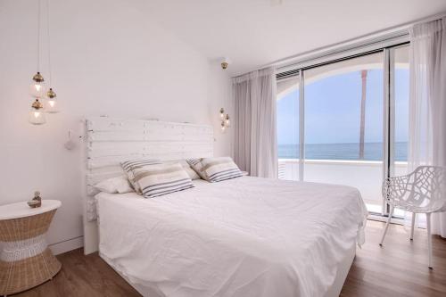 Beautiful 2 bedrooms town house. Frontline beach في مانيلفا: غرفة نوم بيضاء مع سرير ونافذة كبيرة