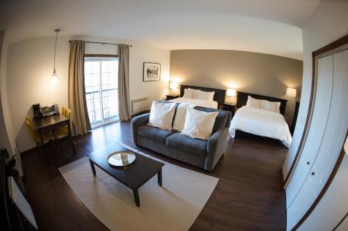 une chambre d'hôtel avec un lit et un canapé dans l'établissement Le Montagnard, Auberge Hôtel & Chalets, à Sutton