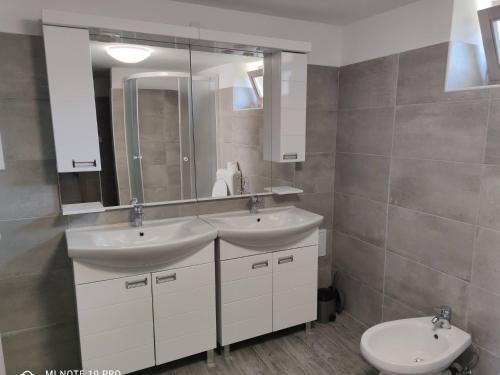 baño con 2 lavabos, espejo y aseo en Das Blaue Haus Guesthouse - Kovácshida en Kovácshida