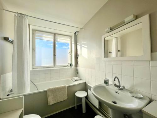 a white bathroom with a sink and a bath tub at COC - Soleil Levant in Wissant