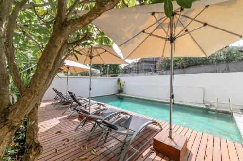 a deck with chairs and umbrellas next to a swimming pool at Beachcove in Pereybere