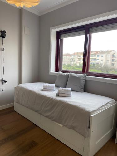 a white bedroom with a bed with two towels on it at Lindo apartamento em Gaia ao lado Bodegas in Vila Nova de Gaia