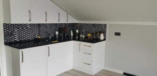 a kitchen with white cabinets and a black counter top at BÖ villa in Macka