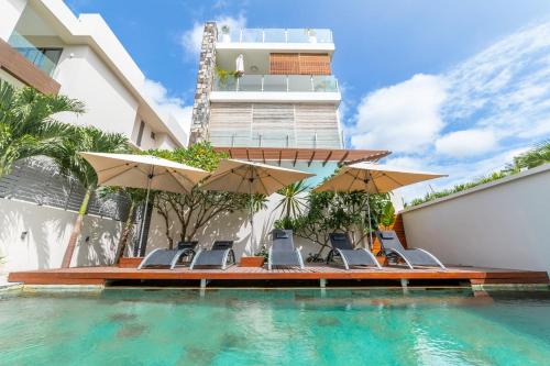 a swimming pool with chairs and umbrellas next to a building at Beachcove No 6 in Grand-Baie