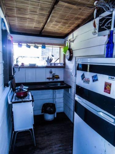 una pequeña cocina con fogones y nevera. en Cabaña en el Bosque de la Viuda, en Punta del Diablo