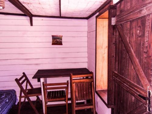 una mesa de madera y sillas en una habitación con puerta en Cabaña en el Bosque de la Viuda, en Punta del Diablo