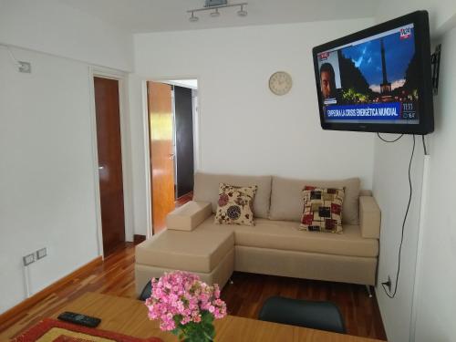 sala de estar con sofá y TV de pantalla plana en APARTAMENTOS TEMPORARIOS EN LA PLATA ( minimo de alquiler 3 dias- La reserva solo se confirma con mensaje al Whasapp de la foto) . Avenida 19 casi 42 La Plata en La Plata