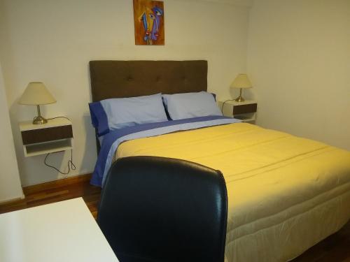 1 dormitorio con 1 cama grande con sábanas azules y amarillas en APARTAMENTOS TEMPORARIOS EN LA PLATA ( minimo de alquiler 3 dias- La reserva solo se confirma con mensaje al Whasapp de la foto) . Avenida 19 casi 42 La Plata en La Plata