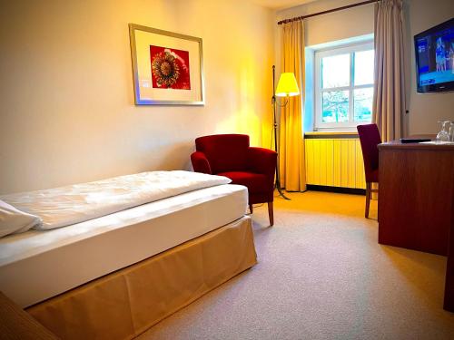 une chambre d'hôtel avec un lit et une chaise dans l'établissement Hotel Gasthof Moosleitner, à Freilassing