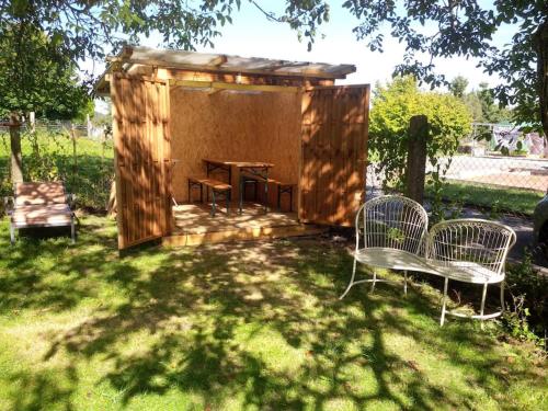 a wooden shed with a table and chairs in a yard at chambre en colocation in Bust