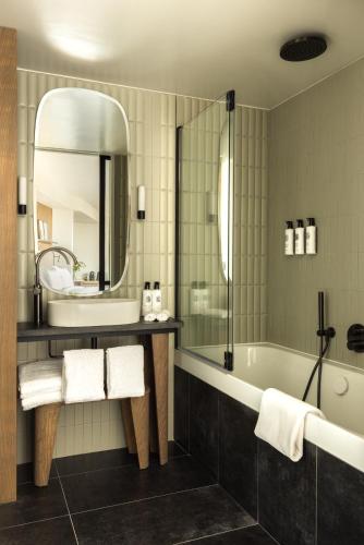 a bathroom with a tub and a sink and a mirror at Hôtel Dame des Arts in Paris