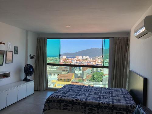 1 dormitorio con cama y ventana grande en LOFT PRAIA GRANDE -, en Arraial do Cabo