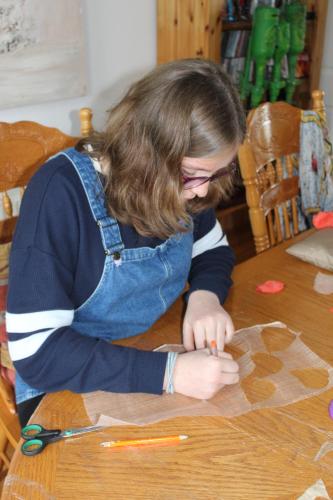 a young girl is sitting at a table cutting paper at Malin Head SolasTobann ArtHouse Room 1 En-suite in Malin Head