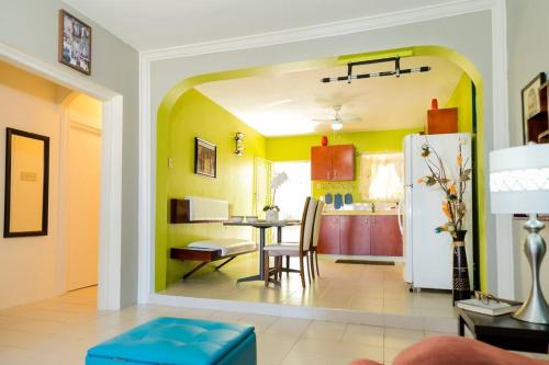 a dining room and kitchen with yellow walls at Hellshire Portmore Vacation Home in Portmore