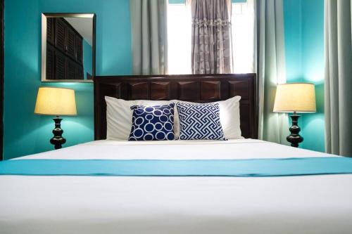 a bedroom with a bed with blue walls and two lamps at Hellshire Portmore Vacation Home in Portmore