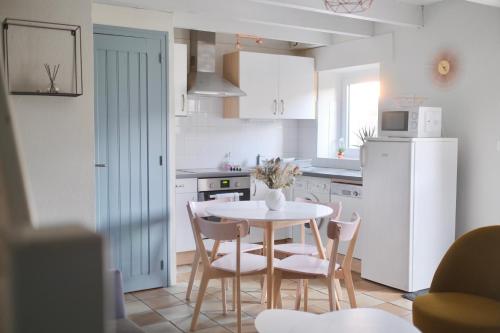 a kitchen with a table and chairs and a white refrigerator at Les Gîtes du Vallon du Trunvel in Plonéour-Lanvern