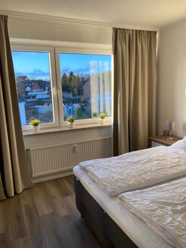 1 dormitorio con 1 cama y 2 ventanas grandes en Küstenbude Sonne, en Grömitz