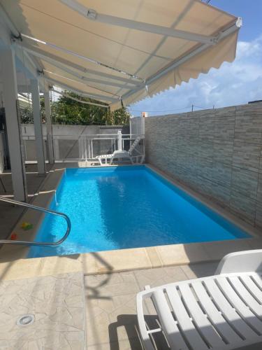 a swimming pool with an umbrella and chairs on a patio at Appartement Hibiscus in Basse-Terre