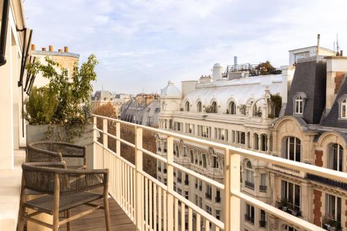 a balcony with two chairs and a view of the city at Hôtel Dame des Arts in Paris
