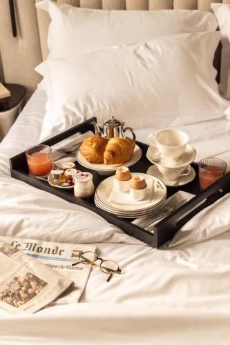 a tray with breakfast foods on a bed at Hôtel Dame des Arts in Paris
