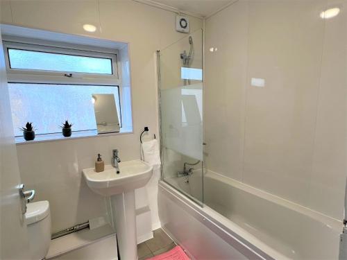 La salle de bains blanche est pourvue d'un lavabo et d'une douche. dans l'établissement Stepney Green Comfy Double bed rooms 14, à Londres