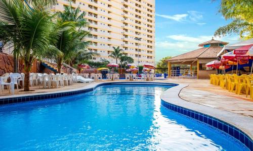 una piscina en un hotel con sillas y sombrillas en Flet Golden Dophin, en Caldas Novas