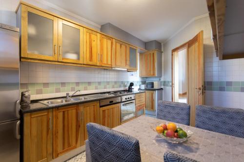 a kitchen with wooden cabinets and a bowl of fruit on a table at Azure - Vista para o Oceano by Smarthomes in São Martinho do Porto