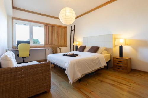 a bedroom with a large bed and a chair at Azure - Vista para o Oceano by Smarthomes in São Martinho do Porto