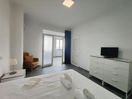 ein weißes Schlafzimmer mit einem Bett und einem TV in der Unterkunft Luxury Port View R31 in Las Palmas de Gran Canaria