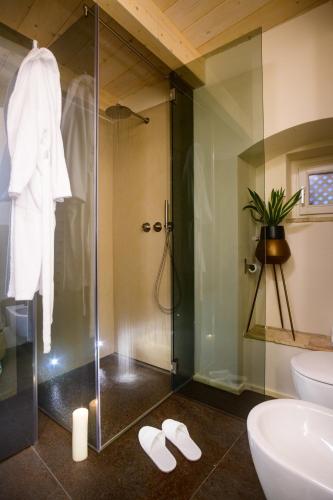 a bathroom with a glass shower with slippers on the floor at Le Malve Cave Retreat in Matera