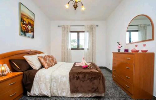 a bedroom with a bed and a dresser and windows at Casa Rural Yeyo en el cráter del volcán in Tinguatón