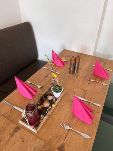Vico's Hotel & Restaurant Asperg في Asperg: طاولة خشبية عليها مناديل وردية