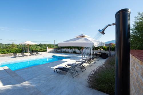 a swimming pool with chairs and umbrellas next to at Vacation villa Matic with 7 bedrooms in Sinj