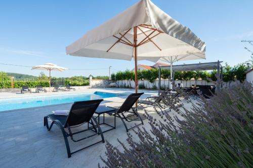 a group of chairs and umbrellas next to a pool at Vacation villa Matic with 7 bedrooms in Sinj
