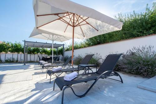 a group of chairs and an umbrella on a patio at Vacation villa Matic with 7 bedrooms in Sinj
