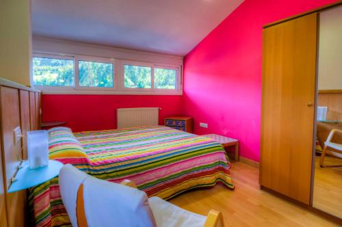 ein Schlafzimmer mit einem Bett und einer rosa Wand in der Unterkunft Apartamentos Turísticos Silvano Posada de Llanes in Posada de Llanes