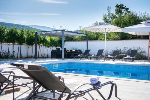 a swimming pool with chairs and umbrellas and a table and a tablektop at Vacation villa Matic with 7 bedrooms in Sinj