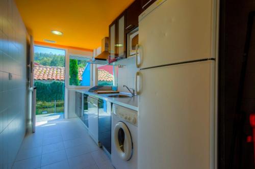 a kitchen with a white refrigerator and a sink at Apartamentos Turísticos Silvano Posada de Llanes in Posada de Llanes