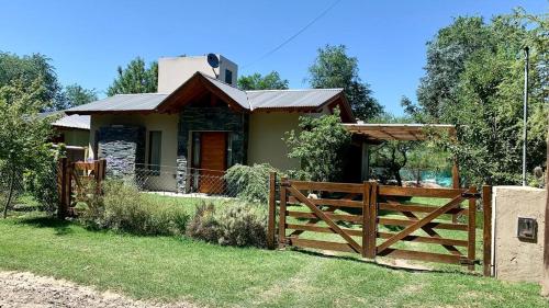 una casa con una valla de madera delante de ella en La Casita de Karen en Villa General Belgrano