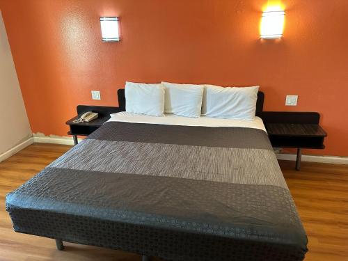 a large bed in a room with an orange wall at Beachside Inn in Anaheim