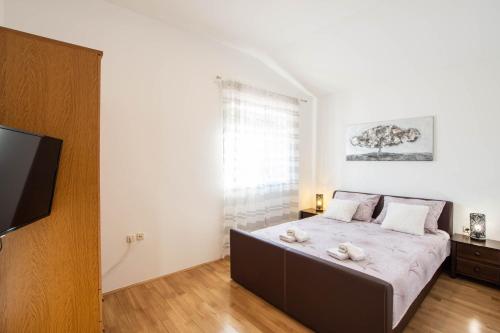 a bedroom with a bed with white sheets and a flat screen tv at Vacation villa Matic with 7 bedrooms in Sinj