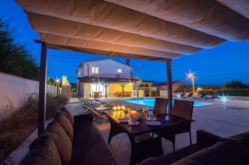 a patio with a table and chairs and a pool at Vacation villa Matic with 7 bedrooms in Sinj