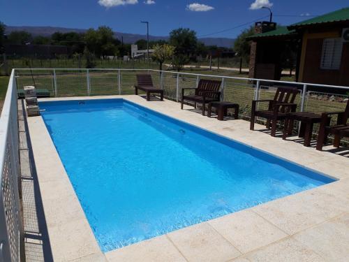 a swimming pool with chairs and a fence around it at Luz Alba Cabañas in Mina Clavero