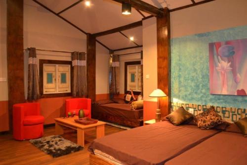 een slaapkamer met een bed, een bank en een tafel bij Cocoville in Pasikuda