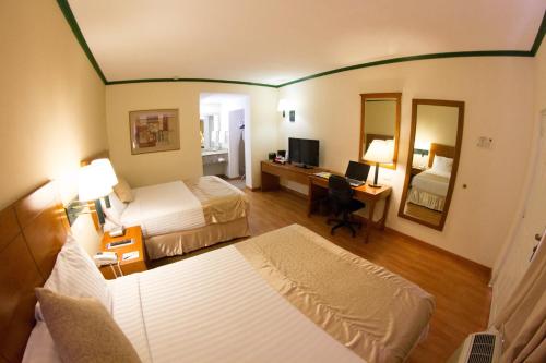 Cette chambre comprend deux lits et un bureau avec un ordinateur. dans l'établissement Hotel Las Misiones, à Monclova