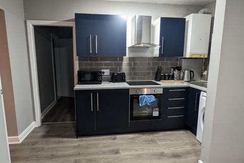 a kitchen with blue cabinets and a stove top oven at Apt 2, Oakwood Residence in Killingbeck