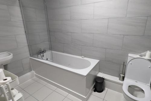 a white bathroom with a tub and a toilet at Apt 2, Oakwood Residence in Killingbeck