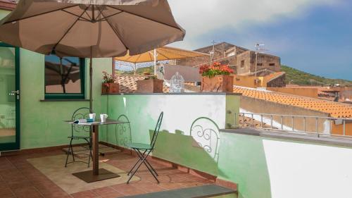 a patio with an umbrella and a table and chairs at Sardinian Gallery Fonte in Bosa