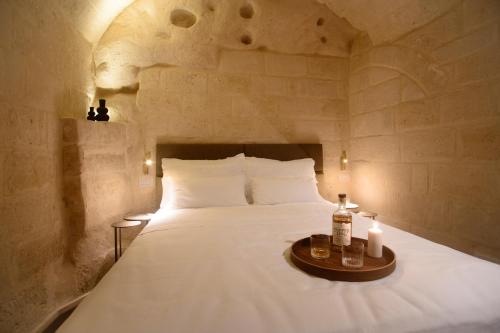 a bedroom with a large white bed with two candles at Le Malve Cave Retreat in Matera